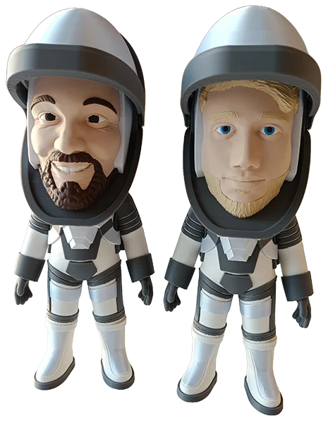 To personlige 3D-printede figurer af mænd i hvide astronautdragter med detaljerede, vellignende ansigter